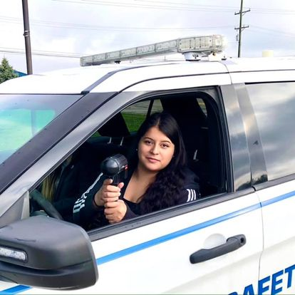 VU alumna Nataly Sandoval trains with a radar gun while sitting in a VU Law Enforcement and Public Safety vehicle